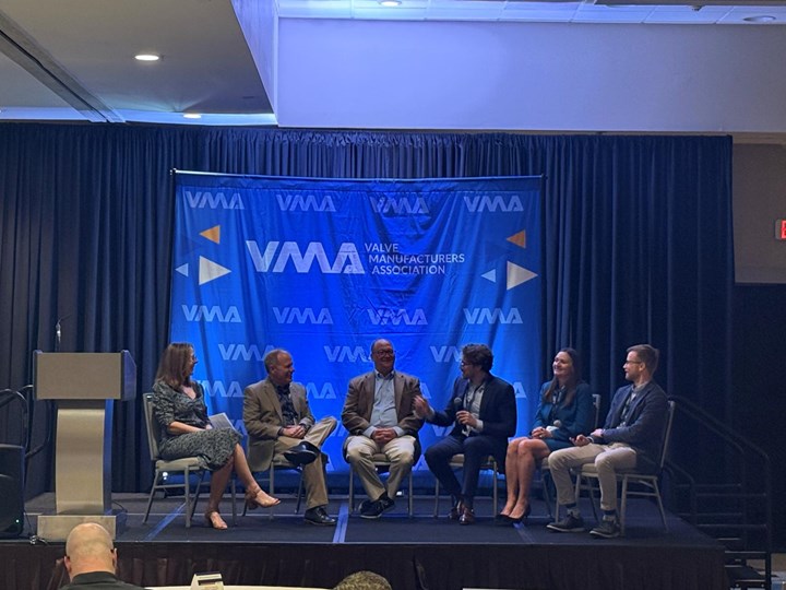 Photo of panelists sitting on a stage speaking in front of VMA blue banner