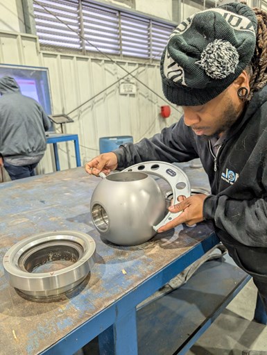 An employee uses a micrometer to inspect a lapped ball for a ball valve.