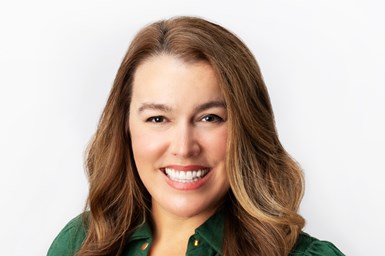 Headshot of Kelly Songer with long dark blonde hair and an emerald green button down shirt.
